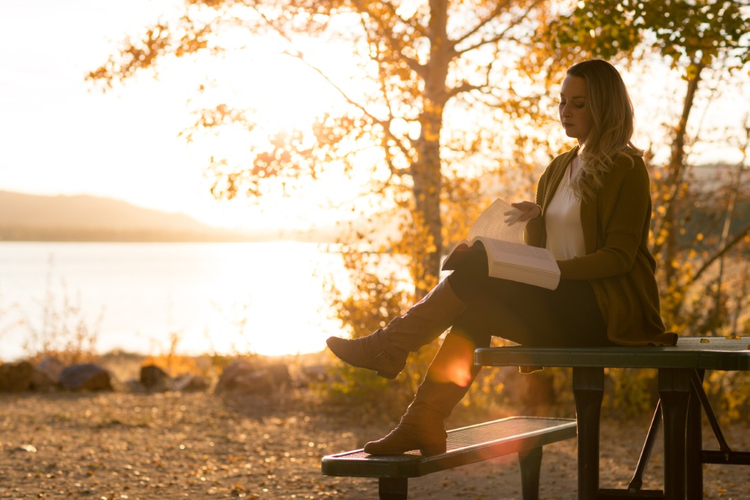 Woman reading book on a park bench